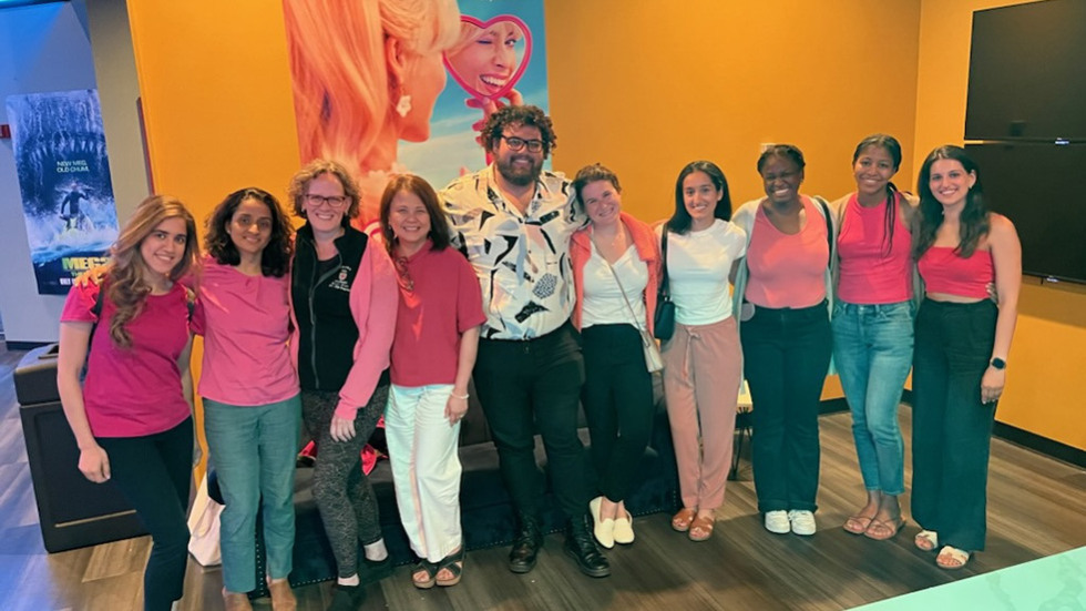 people posing for a photo next to a Barbie poster