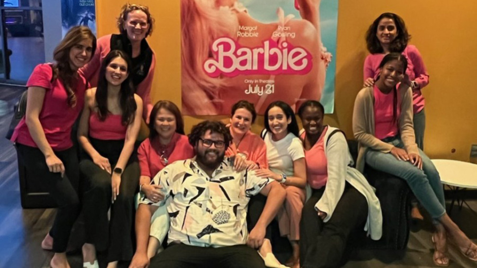 people posing in front of Barbie movie poster