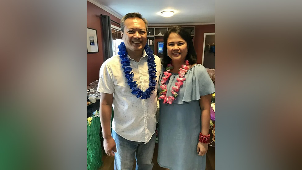 two people wearing Hawaiian leis and posing for a photo