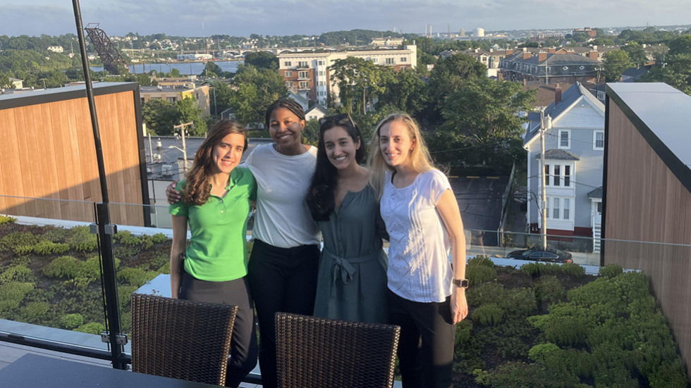 four people posing together on a rooftop